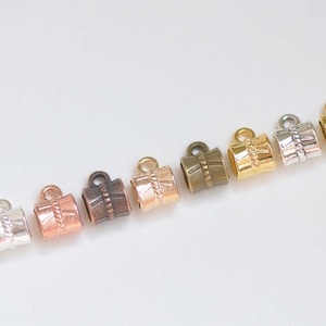 Op de afbeelding: Assortiment van tien metalen koord eindkappen in verschillende afwerkingen, waaronder zilver, goud, koper en brons. Elke dop heeft een decoratief ontwerp.