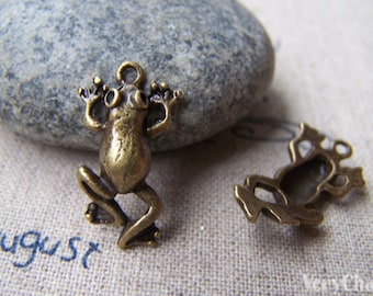 May include: Two antique bronze frog charms. One frog charm is standing on its hind legs with its front legs raised. The other frog charm is lying on its back with its legs in the air.