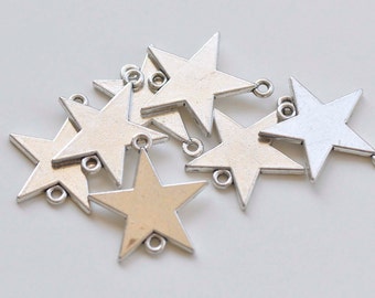 May include: A group of silver star-shaped charms with jump rings. The charms are arranged in a pile, with some overlapping.