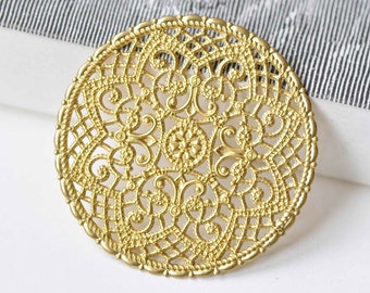 May include: A gold-toned metal filigree circle with a delicate, intricate design. The circle is round and has a smooth, polished finish.