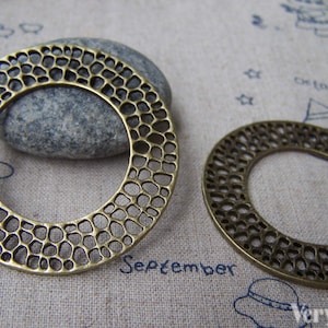 May include: Two antique gold metal rings with a decorative, openwork design. The rings are round and have a textured surface.