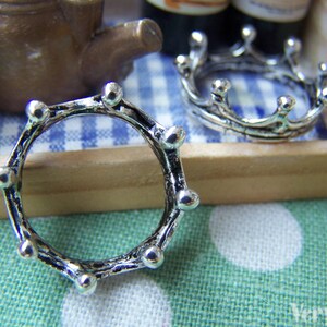 Puede incluir: Dos anillos de plata en forma de corona. El anillo de la izquierda es un c&iacute;rculo simple con una superficie texturizada. El anillo de la derecha tiene un dise&ntilde;o m&aacute;s elaborado con puntos alrededor del c&iacute;rculo.