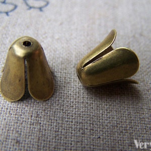 May include: Two gold-colored metal flower-shaped cord ends with a hole in the top.