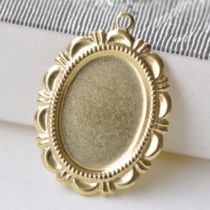 Peut inclure: Pendentif ovale dor&eacute; avec une bordure d&eacute;corative et orn&eacute;e. Le pendentif a une surface lisse et vierge pour ajouter un motif ou une image.