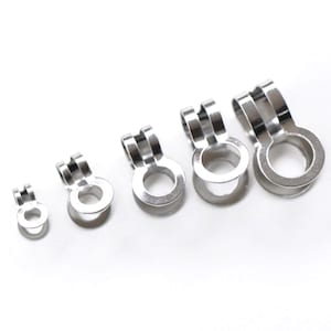 May include: A set of five silver-toned metal ring clips arranged in a row from smallest to largest. Each clip features a circular base with a U-shaped attachment point extending upwards, designed for securing or connecting items with a metallic finish.
