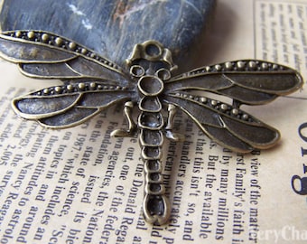 May include: A bronze dragonfly charm with intricate details and a textured finish. The dragonfly has a detailed body and wings with small beads along the edges.