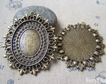 May include: Two antique gold-toned metal pendant trays with ornate designs. One tray is oval shaped with a smooth center, the other is round with a textured center.