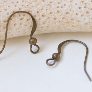 May include: Two bronze earring hooks with a small ball at the top of each hook.