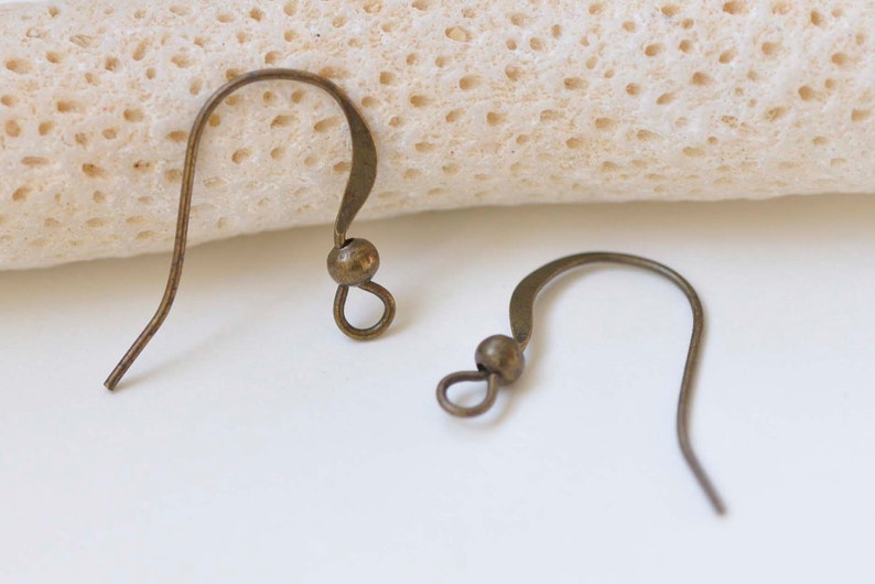 May include: Two bronze earring hooks with a small ball at the top of each hook.