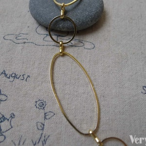 May include: Gold chain necklace with oval and round links. The chain is on a beige fabric background with the words "August" and "September" written on it.