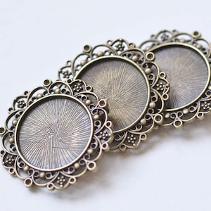May include: Three antique gold-toned metal round pendant trays with ornate filigree designs. The trays have a smooth, slightly textured surface.