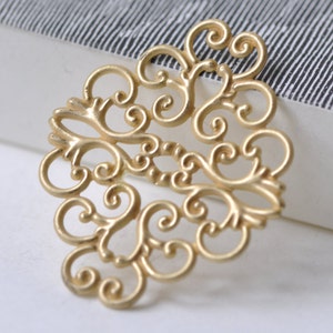Könnte beinhalten: Goldenes Filigran-Anhänger mit einem zarten, filigranen Design. Der Anhänger ist aus Metall und hat eine glänzende Oberfläche.