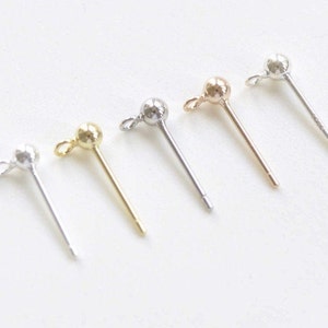 May include: Five earring posts with a small ball at the top. The posts are in different colors: silver, gold, rose gold, and two more silver.