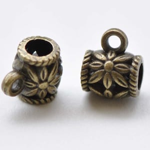 May include: Two antique bronze-coloured metal bead caps. Each cap features a floral design with a rope-like border. One has a loop, the other has a small ring. These decorative components are used in jewellery making.