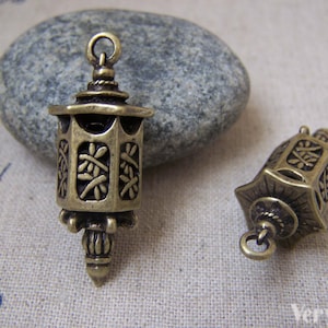 Puede incluir: Dos abalorios de metal de color dorado antiguo con forma de faroles con diseños intrincados. Los abalorios tienen un bucle en la parte superior para sujetarlos a joyas u otras manualidades.