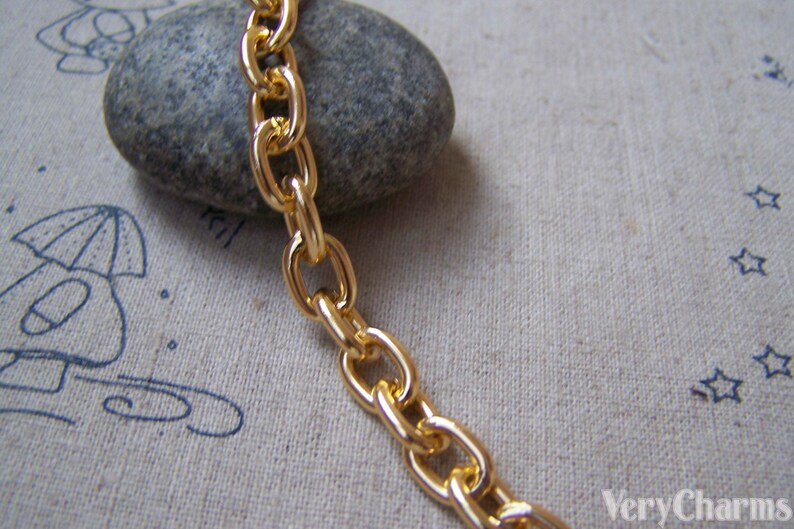 May include: Gold chain link with a smooth, polished finish. The chain is lying on a textured fabric surface.