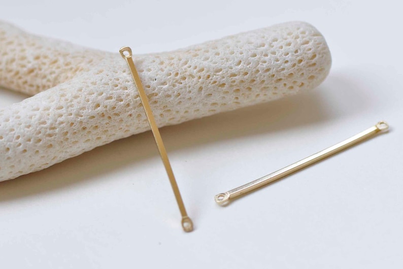 May include: Two gold metal connector bars with loops at each end. The bars are straight and have a smooth finish.