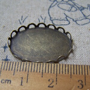 May include: A round, antique gold-coloured metal tray with a scalloped edge. The tray measures approximately 2 cm in diameter.