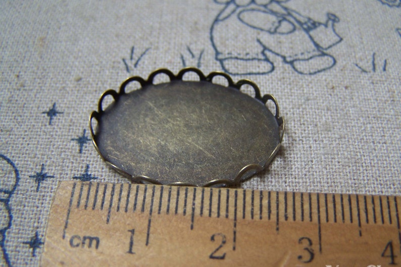 May include: A round, antique gold-coloured metal tray with a scalloped edge. The tray measures approximately 2 cm in diameter.