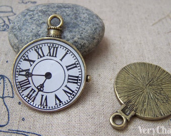 May include: A bronze-colored clock face pendant with Roman numerals and a black clock hand. The back of the pendant is a solid bronze color with a textured surface. The pendant has a loop for attaching to a chain or cord.