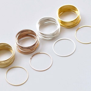 Puede incluir: Un conjunto de tres anillos metálicos de diferentes colores. Los anillos están apilados en tres pilas, con los anillos dorados a la izquierda, los anillos plateados en el medio y los anillos de oro rosa a la derecha. También hay tres anillos individuales, uno de cada color, en la fila inferior.