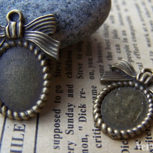 Könnte beinhalten: Zwei antike ovale Bilderrahmen-Anhänger aus Bronze mit Schleifendetail. Die Rahmen haben einen Durchmesser von etwa 3,8 cm.
