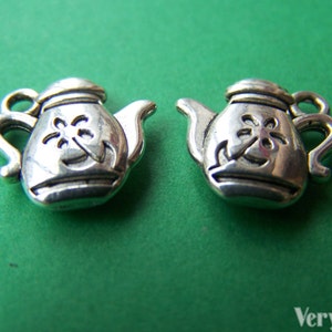 May include: Two silver teapot charms with a flower design. The charms are about 1 inch in size.