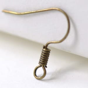Puede incluir: Un gancho para pendientes de color dorado con cierre de resorte. El gancho está hecho de metal y tiene un acabado liso.