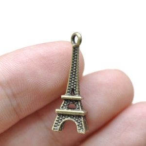 May include: A bronze-colored Eiffel Tower charm with a loop at the top for attaching to a necklace or bracelet.