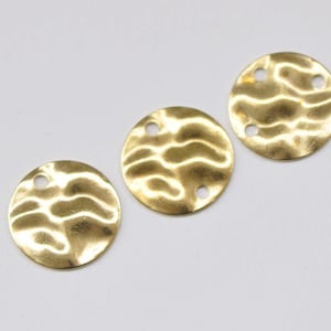 Könnte beinhalten: Drei goldfarbene Metallkreise mit einer strukturierten Oberfläche und jeweils zwei Löchern. Die Kreise sind in einer Reihe angeordnet.