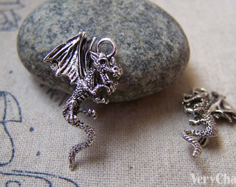 May include: Two silver dragon charms with wings outstretched. The dragon on the left is facing right and has a loop at the top for attaching to a necklace or bracelet. The dragon on the right is facing left and has a loop at the top for attaching to a necklace or bracelet.