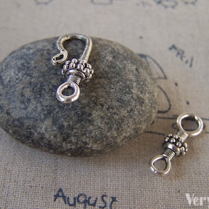 May include: Two silver-toned metal clasps with a beaded design. The clasps are used for jewelry making.