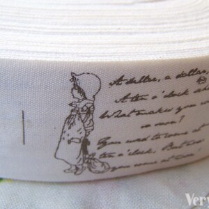 May include: White cotton ribbon with a brown print of a girl in a dress and a hat. The ribbon has a handwritten text that reads "At a dollar, a dollar, at the 1 o'clock, what makes you so rare? You need to come at the 1 o'clock, but I don't want to come at once."