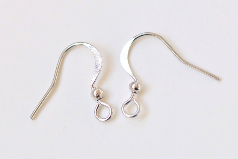 May include: Two silver earring hooks with a small ball at the top of the hook.