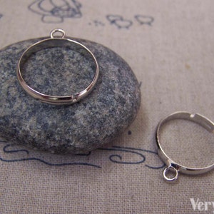 Puede incluir: Dos blancos de anillo de metal plateados con un anillo de salto unido a la parte superior. Los anillos son redondos y tienen un acabado liso.