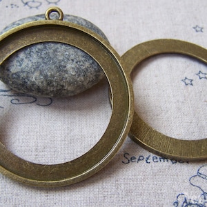 May include: Two antique gold-toned metal round picture frames with a loop at the top for hanging. The frames are empty and ready to be filled with your favorite photos or artwork.