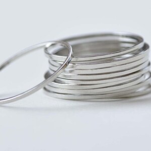 Può includere: Un set di anelli d'argento, ogni anello è una sottile fascia di metallo.