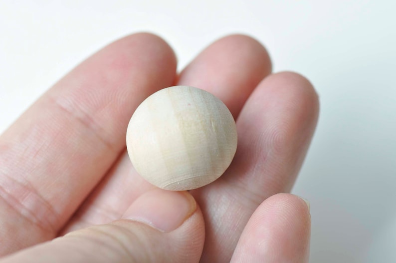 Puede incluir: Primer plano de una bola redonda de madera lisa. La bola es de color marr&oacute;n claro y tiene una superficie ligeramente texturizada.