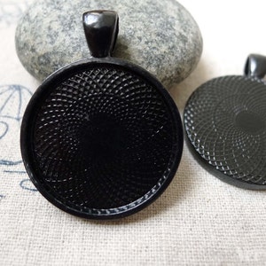 Puede incluir: Dos bandejas redondas de metal negro para colgantes con una superficie texturizada. Las bandejas tienen un bucle en la parte superior para colgar.