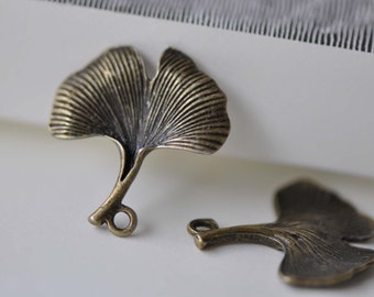 May include: Two antique bronze ginkgo leaf charms with a detailed vein pattern. Each charm has a small loop for attaching to jewelry or other crafts.