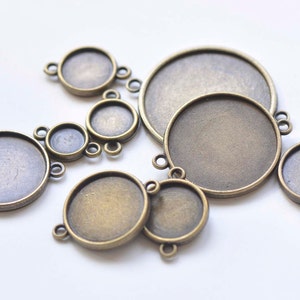 May include: An assortment of antique bronze-toned round bezel trays in various sizes. Each tray has a flat, recessed area for setting a design and small loops for attaching to other components. Ideal for jewelry making.