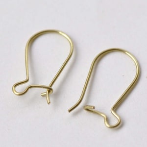 Könnte beinhalten: Zwei goldfarbene Ohrhaken, jeder mit einer einfachen, abgerundeten Form.