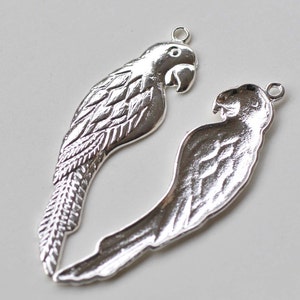 May include: Two silver parrot charms with detailed wing and feather designs. The charms have a loop at the top for attaching to jewelry or other crafts.