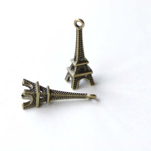 May include: Two small, gold-colored Eiffel Tower charms. The charms are detailed and have a textured surface.