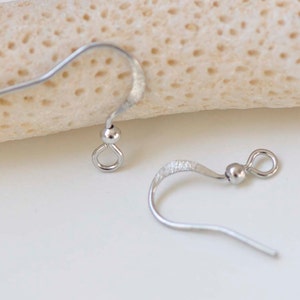 May include: Two silver earring hooks, one with a smooth finish and the other with a textured finish.
