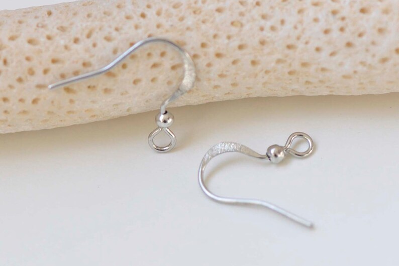 May include: Two silver earring hooks, one with a smooth finish and the other with a textured finish.