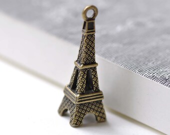 Peut inclure: Un charme en métal doré en forme de Tour Eiffel. Le charme a un design détaillé et une boucle en haut pour l'attacher à un collier ou un bracelet.