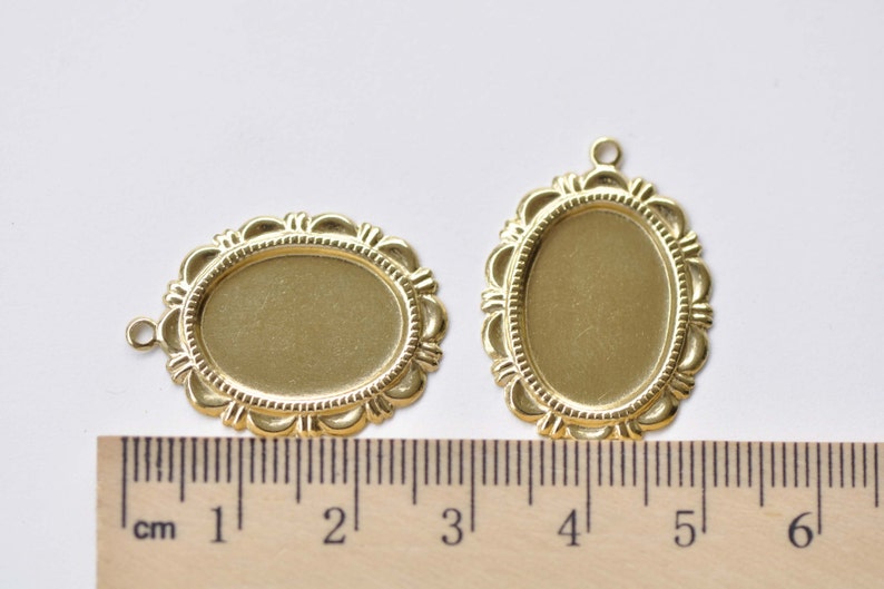 Peut inclure: Deux cadres ovales en m&eacute;tal de couleur dor&eacute;e avec des bords d&eacute;coratifs. Les cadres mesurent environ 5 cm et 10 cm de long. Une r&egrave;gle est visible pour l'&eacute;chelle.