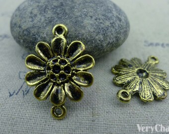 May include: Two antique gold-toned metal flower charms with three jump rings. The charms are in the shape of a daisy with a raised center and textured petals.