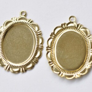 Peut inclure: Deux plateaux de pendentif ovales en m&eacute;tal de couleur dor&eacute;e avec un bord festonn&eacute; d&eacute;coratif. Les plateaux sont vierges et pr&ecirc;ts &agrave; &ecirc;tre remplis de r&eacute;sine, de photos ou d'autres embellissements.